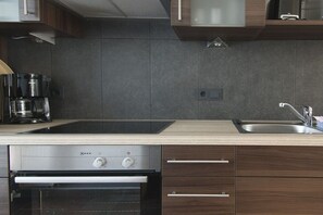 A modern kitchen with a built-in oven, a coffee maker, and a sink. - Sauna house in Wehldorf (Wurster Nordseeküste)