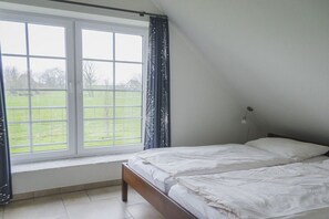 A bedroom with a large window, a bed, and a bedside table. - Sauna house in Wehldorf (Wurster Nordseeküste)