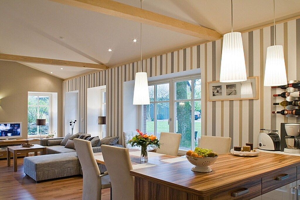 A modern living room with a wooden dining table, comfortable seating, and large windows.