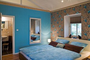 A bedroom with a bed, a mirror, a window, and a bathroom visible through an open door. - Pond View - Gundies Home No. 15 Ltd (Klein Meckelsen)