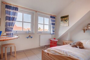 Une chambre à coucher avec un lit, un bureau et deux fenêtres avec des rideaux.