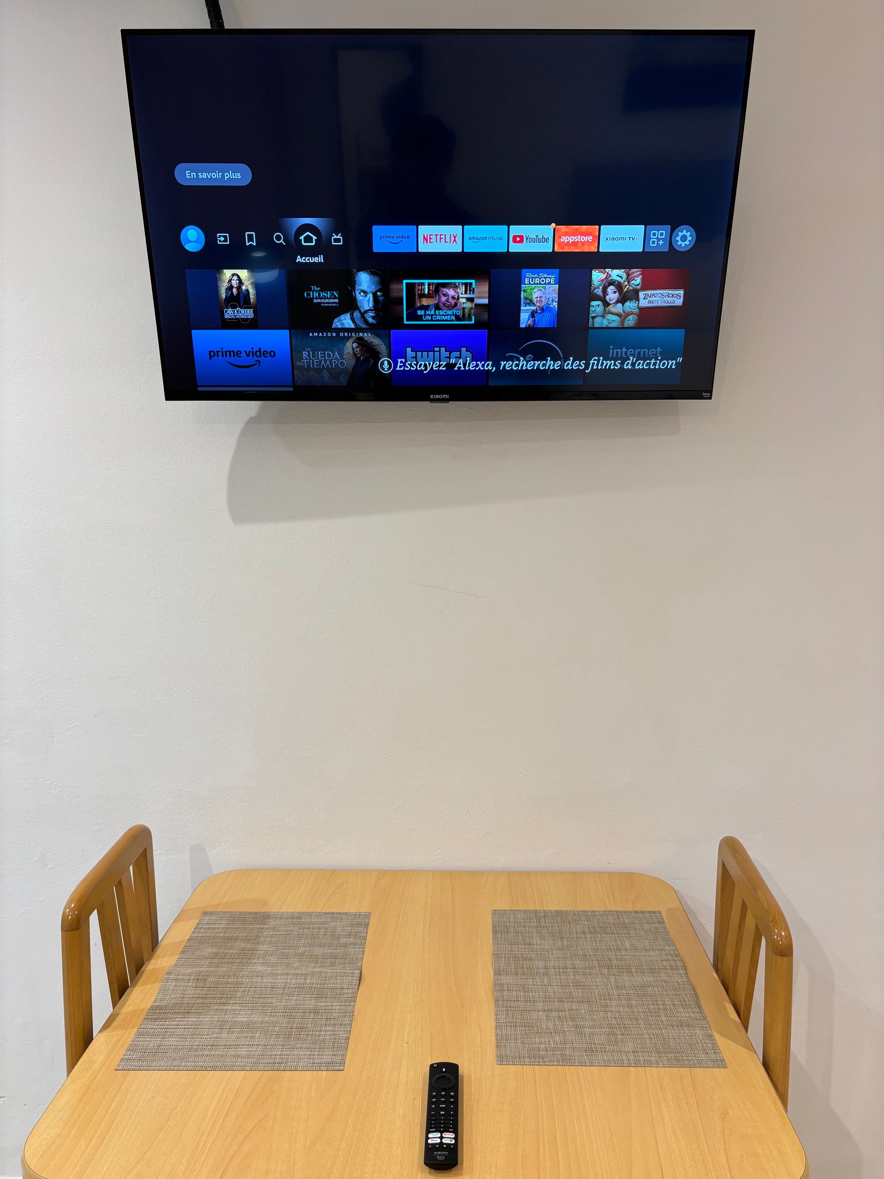 Un téléviseur à écran plat fixé au mur, affichant différentes plateformes de diffusion en continu.