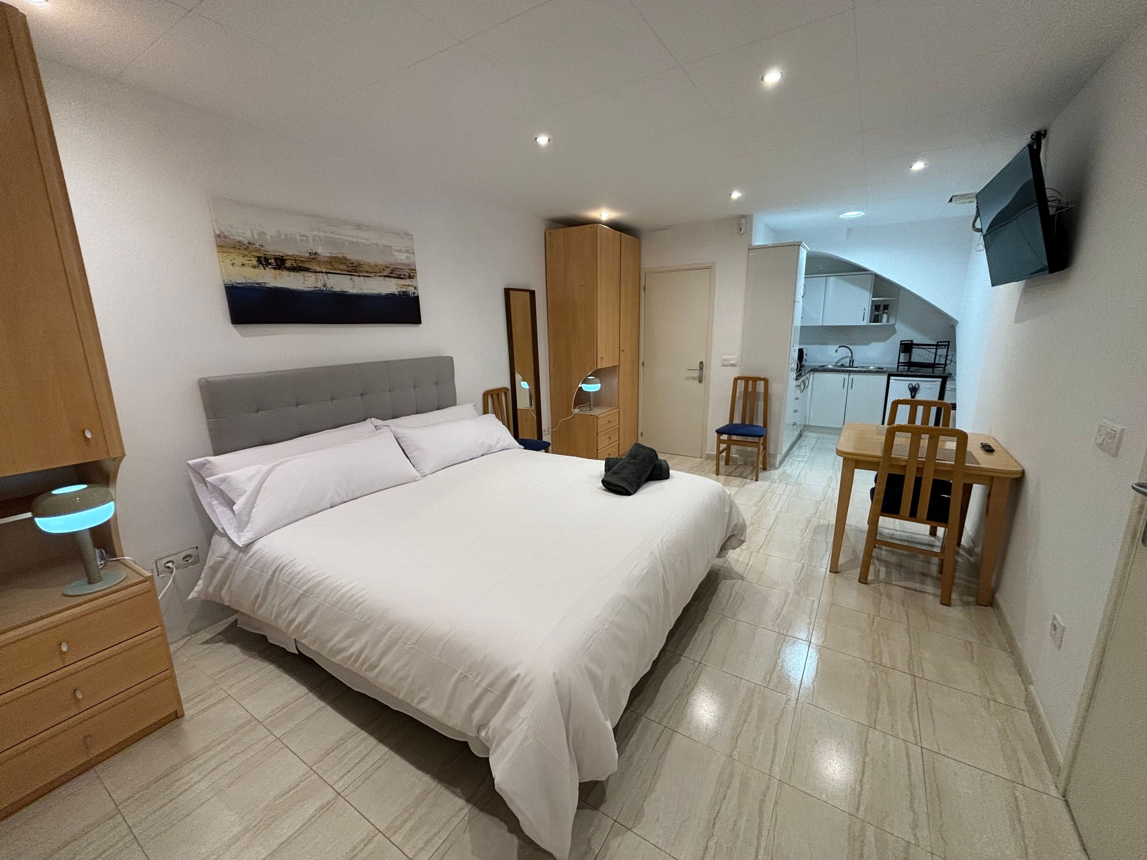Une chambre d’hôtel avec un lit, une table de chevet, une lampe et une vue sur la cuisine.