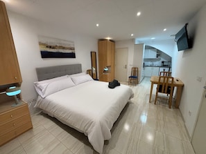 Une chambre d’hôtel avec un lit, une table de chevet, une lampe et une vue sur la cuisine.