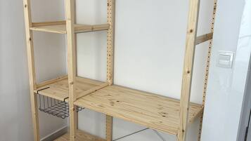 A wooden shelving unit with multiple shelves, a metal wire shelf, and a white wall background.