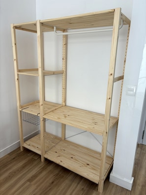Een houten rek met meerdere planken, een metalen draadplank en een witte achtergrond.