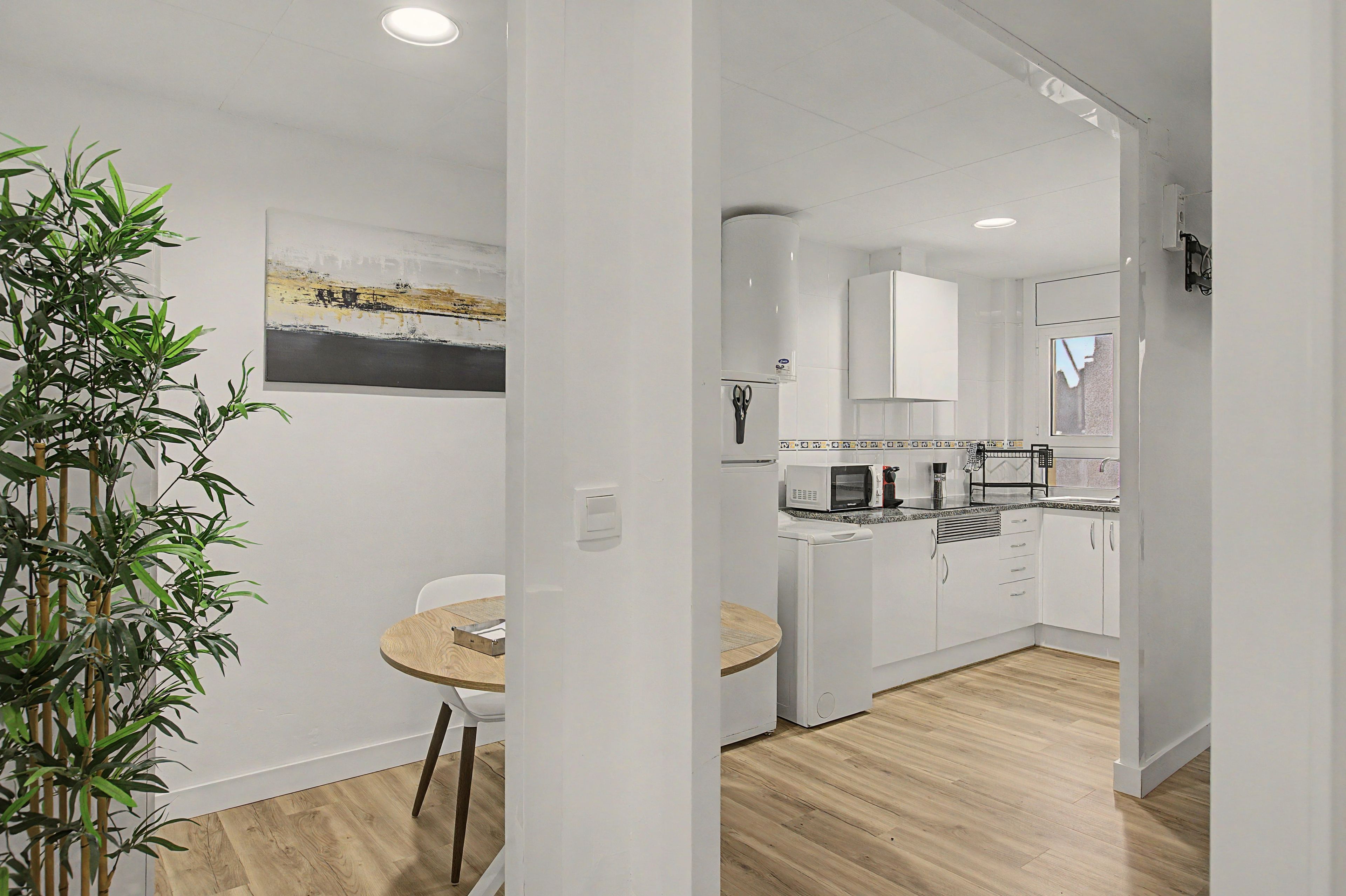 A modern kitchen with white cabinets, a microwave, and a coffee machine.