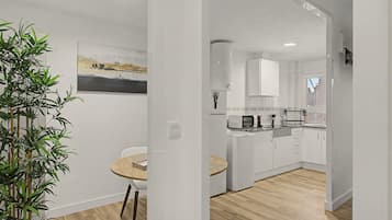 A modern kitchen with white cabinets, a microwave, and a coffee machine.