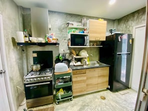 A compact kitchen with a stove, microwave, refrigerator, and wooden cabinets. - Serene 2-bedroom House Rental in Bang Kaeo, Thailand (Bang Phli)