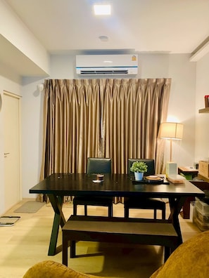 A room with a dark wooden table, two chairs, a potted plant, and a lamp on a side table. - Serene 2-bedroom House Rental in Bang Kaeo, Thailand (Bang Phli)