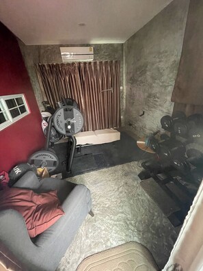 A gym with a bench press, a squat rack, and a wall-mounted air conditioner. - Serene 2-bedroom House Rental in Bang Kaeo, Thailand (Bang Phli)