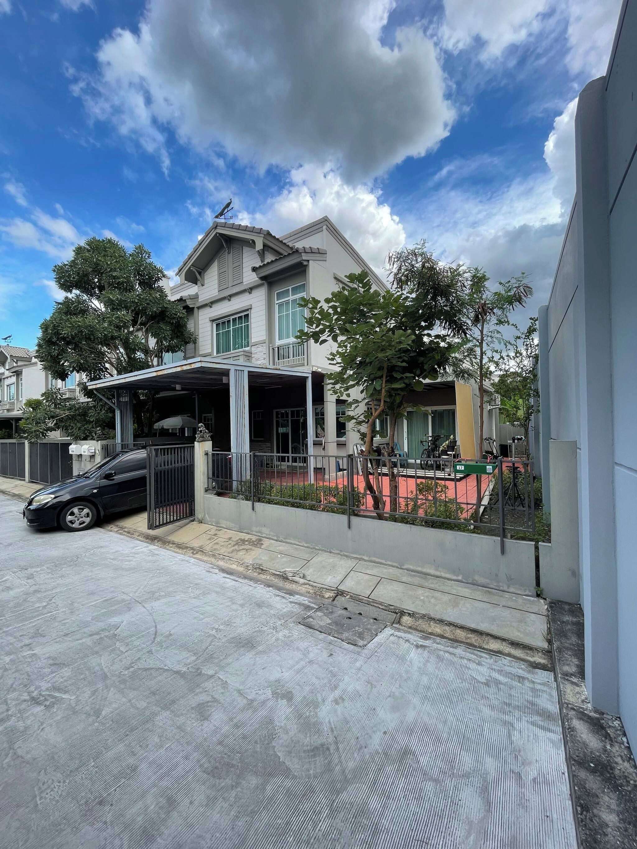 A residential building with a covered driveway, a gated entrance, and a parked car.