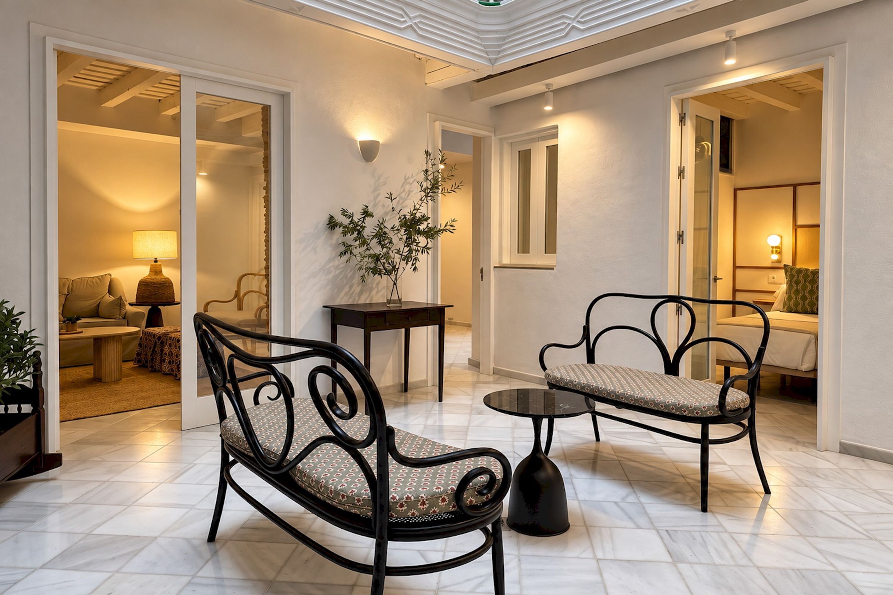 A spacious living area with a high ceiling, a round coffee table, two upholstered chairs, a side table, and a potted plant.