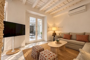 A living room with a flat-screen TV, a sofa, a coffee table, and a patterned rug. - Genteel Home Patio del Arenal 001 (Seville)