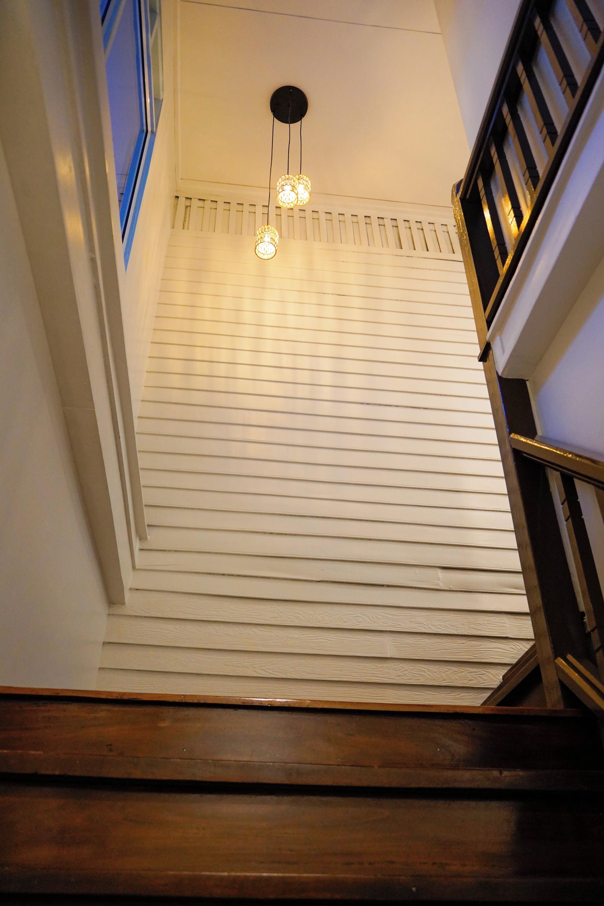 A staircase with a wooden handrail and a light fixture with three bulbs.