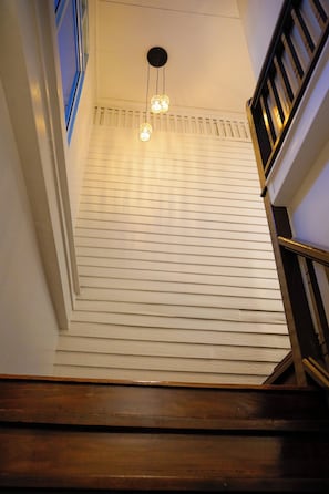 Una escalera con barandilla de madera y una lámpara con tres bombillas.