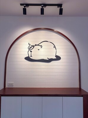 Una pared con un marco de madera y un panel blanco con el perfil negro de un cerdo.