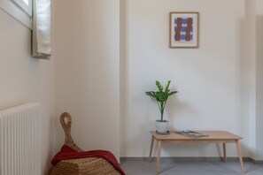 A corner room with a radiator, a woven basket with a red cloth, a small wooden table with a plant and a magazine, and a framed artwork on the wall. - iFlat | Scenic Penthouse with Terrace near Vatican (Rome)