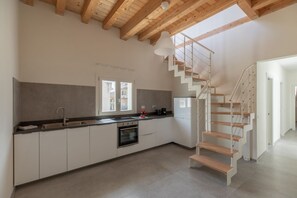 Une cuisine moderne équipée d’un four encastré, d’un évier et d’un escalier menant à un niveau supérieur.