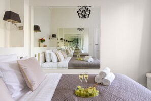 A hotel room with a large bed, a mirror, a chandelier, and a tray with grapes and champagne glasses. - Lumina 2room Apt w/ Parking near center (Warszawa)