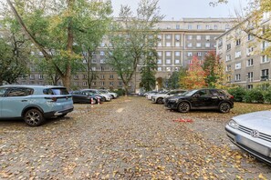 A parking area with multiple cars and a building with multiple windows in the background. - Lumina 2room Apt w/ Parking near center (Warszawa)