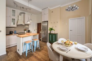 Une cuisine moderne dotée d’un îlot central, de tabourets de bar et d’un coin repas avec une table ronde pouvant accueillir six personnes.