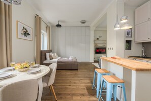 A modern kitchen with a wooden countertop, bar stools, and a dining area with a round table set for two. - Lumina 2room Apt w/ Parking near center (Warszawa)