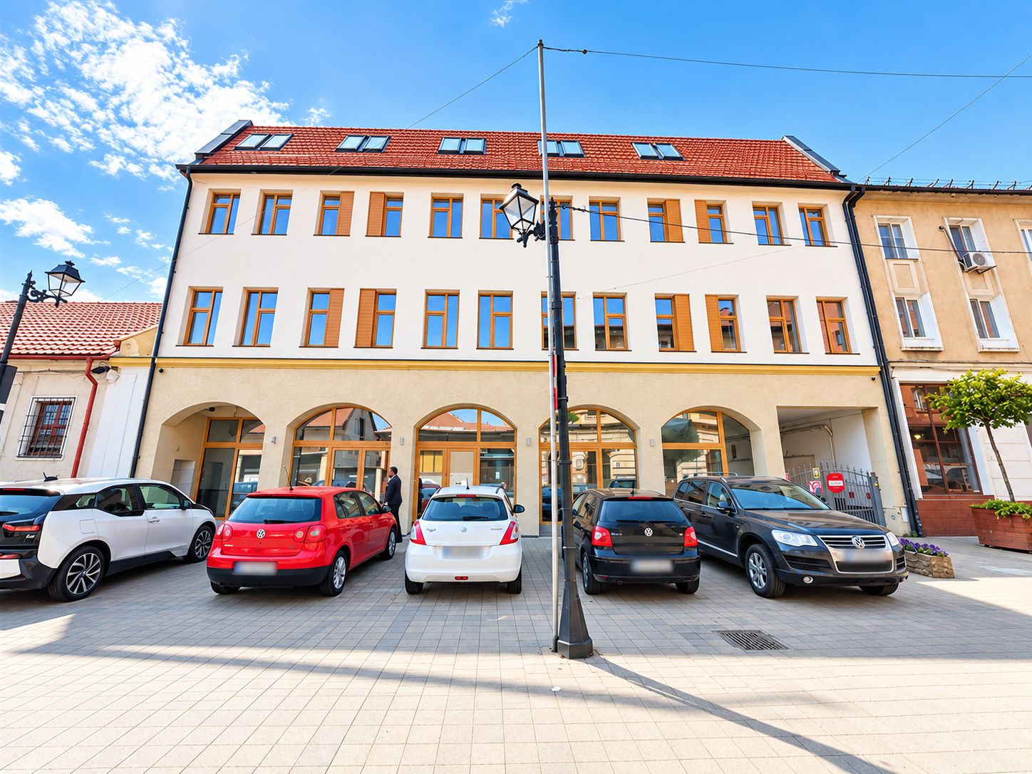 A multi-story building with a row of parked cars in front.
