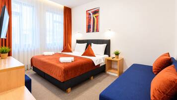 A hotel room with a bed, bedside table, and a blue sofa.
