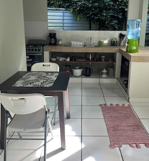 A compact kitchen with a gas stove, coffee maker, and various kitchenware on shelves. - Private Jungle Retreat w Lagoon, Walk to Beach (Cocles)
