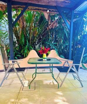 An outdoor seating area with a table and chairs, surrounded by tropical plants. - Private La Cantina Loft (Limón)