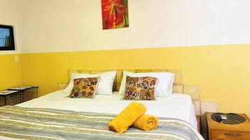 A hotel room with a bed, a nightstand, a painting on the wall, and a window.
