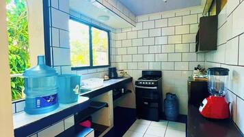 A compact kitchen with a gas stove, a water dispenser, and a blender on the counter.