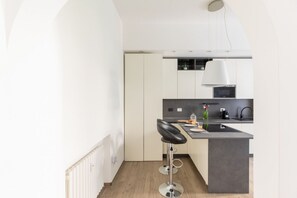 Una cucina moderna con isola centrale, sgabelli da bar e lampadario a sospensione.