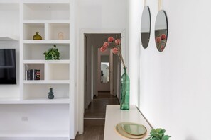 A hallway with white shelving units, a green vase, and a mirror. - iFlat | Sleek & Sunlit Apartment near the Vatican (Rome)