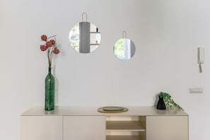 A minimalist room with a white wall, a green vase with dried flowers, and two round mirrors. - iFlat | Sleek & Sunlit Apartment near the Vatican (Rome)