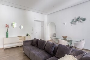 A modern living room with a grey sofa, a glass dining table, and minimalist decor. - iFlat | Sleek & Sunlit Apartment near the Vatican (Rome)
