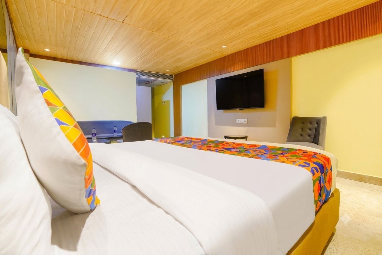 Una habitación de hotel con una cama, un escritorio, una silla y un televisor en la pared.