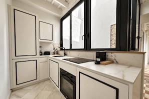 A modern kitchen with white cabinetry, a black countertop, and a large window. - Genteel Home Patio del Arenal Terrace 301 (Seville)