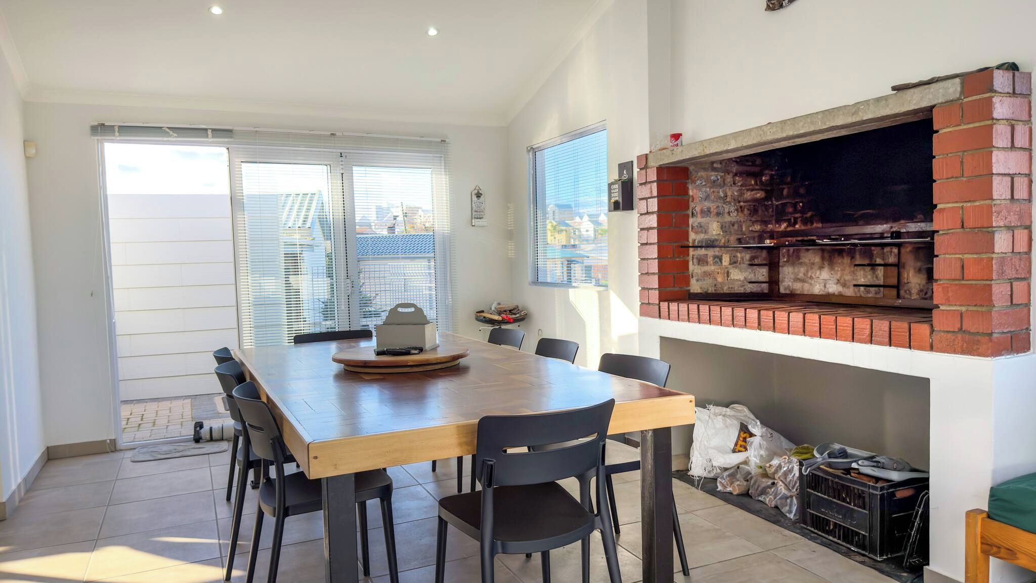 Un coin repas avec un four en briques, une table en bois et des chaises noires.