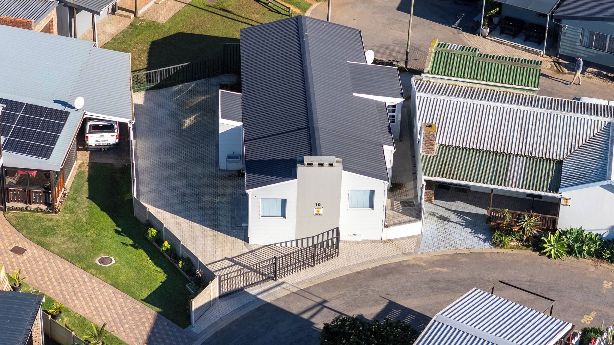 A residential area with multiple houses, a paved driveway, and a solar panel installation.