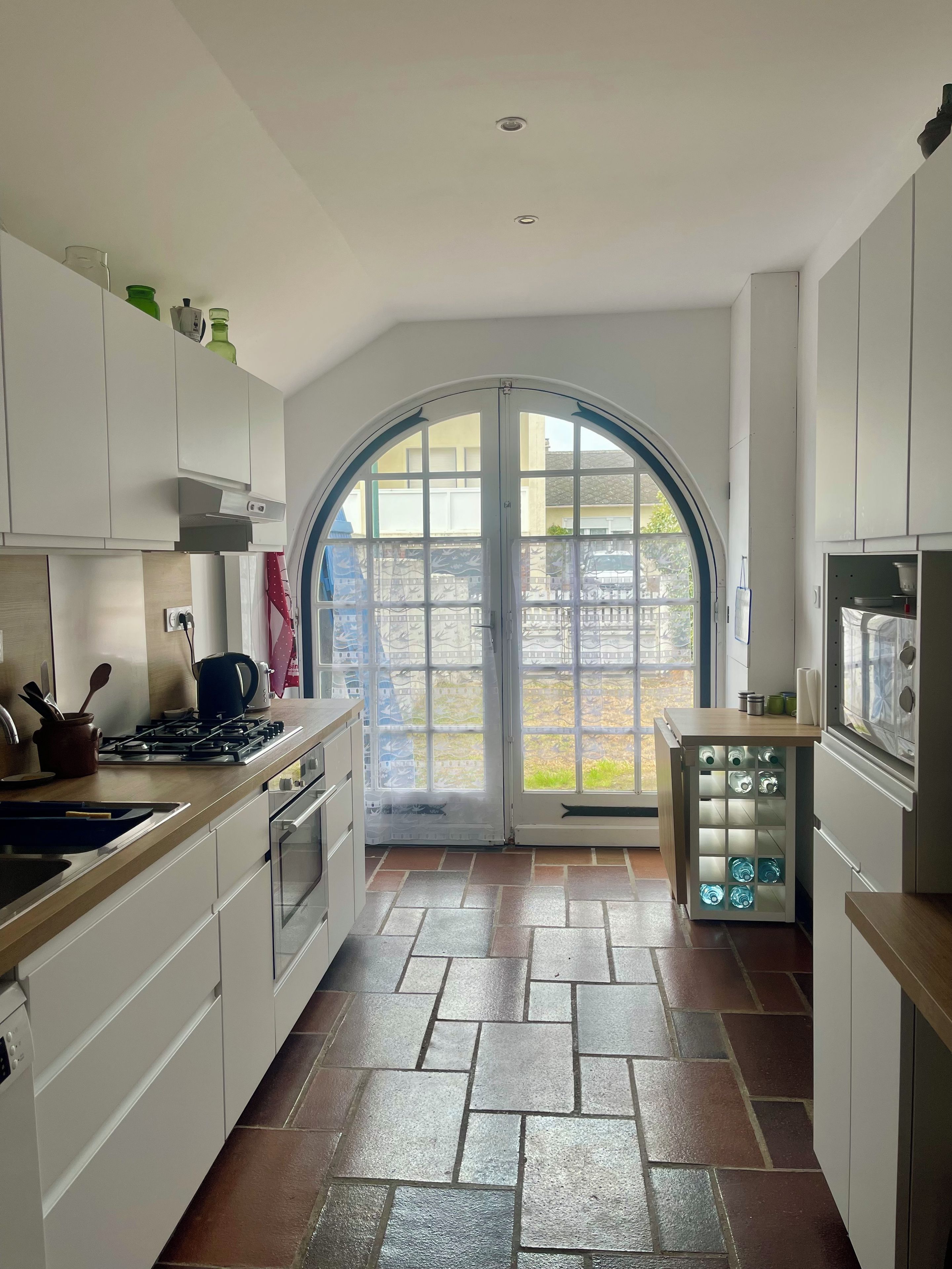 A kitchen with white cabinets, a gas stove, and a tiled floor.