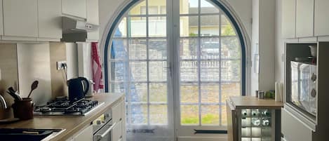 A kitchen with white cabinets, a gas stove, and a tiled floor.