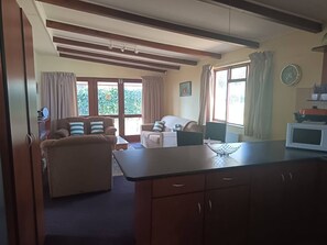 Een ruime woonkamer met een bank, een eettafel en een keukentafel.