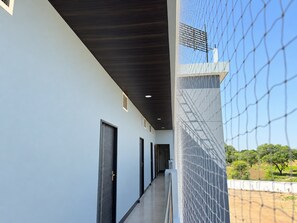 Un pasillo con puertas, un techo con iluminación empotrada y vistas a un área exterior cercada.