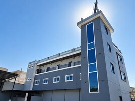 Un edificio de varios pisos con una llamativa banda vertical azul, balcones y cielo despejado.