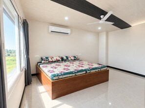 Un dormitorio con cama, aire acondicionado, ventilador de techo y vistas al exterior.