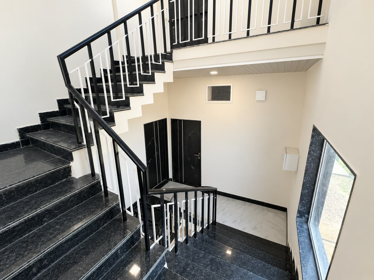 A staircase with black railings and marble steps leading to an upper floor.