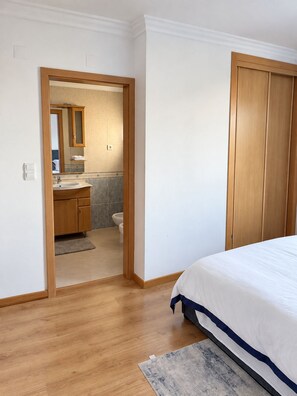 A bedroom with a wooden floor, a bed with white bedding, and a wooden wardrobe. - Cavaleiros Premiun Stay (Santo António dos Cavaleiros)