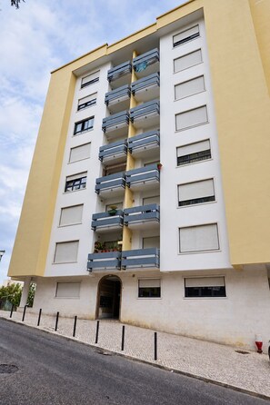 A multi-story building with balconies, a ground entrance, and a paved sidewalk. - Cavaleiros Premiun Stay (Santo António dos Cavaleiros)